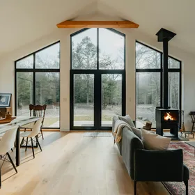 A living room with tall windows and a wood stove