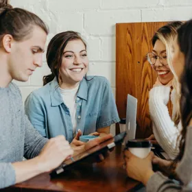 Friends talking over coffee and a laptop