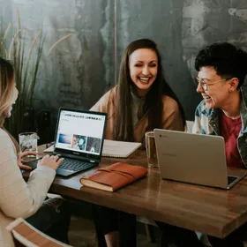 Three people laughing together over laptops